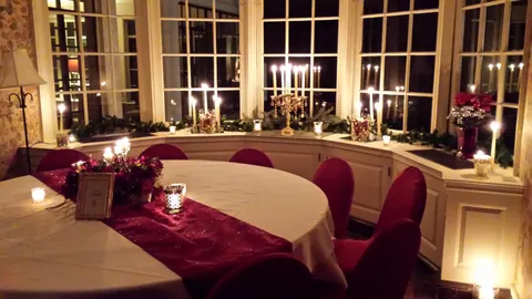 The ballroom at night, candlelight and white linens along the curved window wall