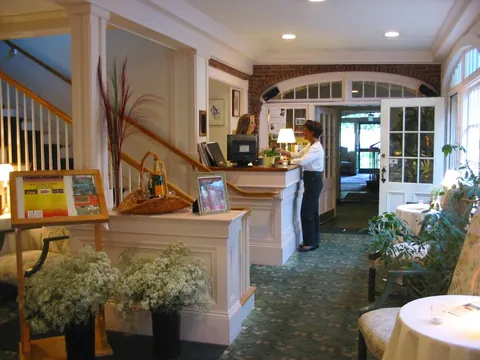 The front desk at The Governor's Inn, a guest checking in beside the original staircase