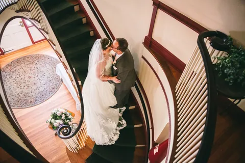 A bride and groom on the spiral staircase at The Governor's Inn, photographed from the landing above